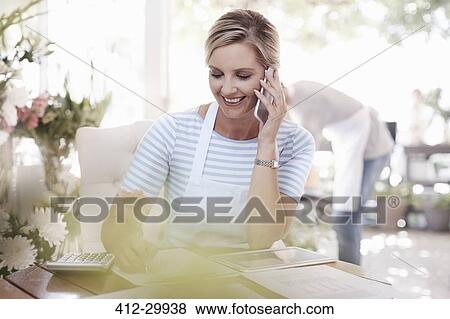 Florist talking on cell phone in flower shop View Large Photo Image Stock Photo - Florist talking on cell phone in flower shop. Fotosearch