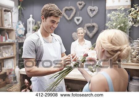 Florist tying flowers for woman in flower shop View Large Photo Image Stock Photo - Florist tying flowers for woman in flower shop. Fotosearch
