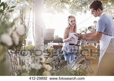 Florist with digital tablet talking to customer with bicycle View Large Photo Image Stock Image - Florist with digital tablet talking to customer with bicycle. Fotosearch