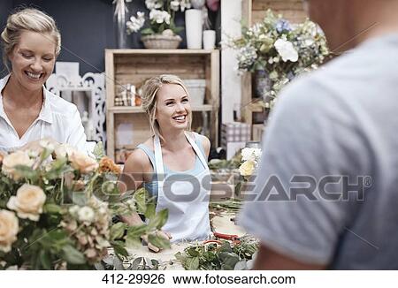 Stock Photograph - Florists arranging bouquet and talking to customer in flower shop. Fotosearch