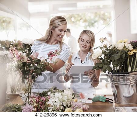 Florists with digital tablet arranging bouquet in flower shop View Large Photo Image Stock Photograph - Florists with digital tablet arranging bouquet in flower shop. Fotosearch