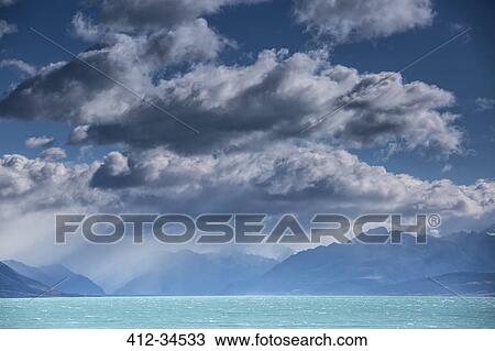 Stock Image - Fluffy clouds above tranquil blue Lake Pukaki, South Island, New Zealand. Fotosearch