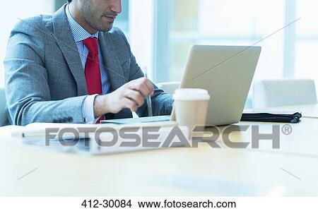 Focused businessman working at laptop in conference room View Large Photo Image Picture - Focused businessman working at laptop in conference room. Fotosearch