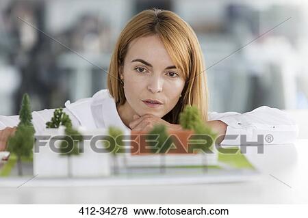 Focused female architect examining model View Large Photo Image Stock Photo - Focused female architect examining model. Fotosearch