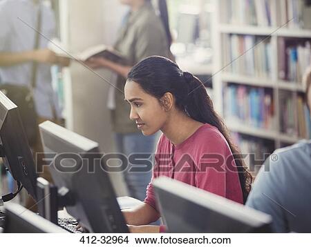 Picture - Focused female college student researching using computer in library. Fotosearch