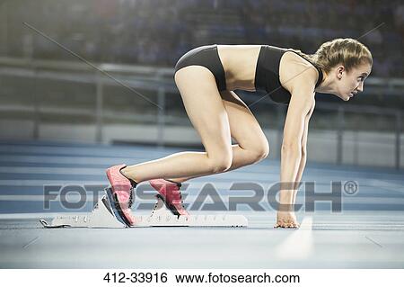 Focused female runner ready at starting block on sports track View Large Photo Image Stock Photograph - Focused female runner ready at starting block on sports track. Fotosearch