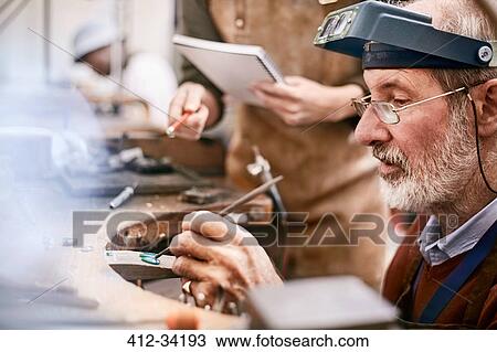 Stock Image - Focused jeweler working in workshop. Fotosearch