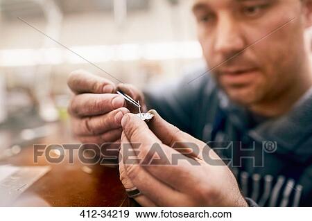 Focused male jeweler assembling jewelry in workshop View Large Photo Image Stock Photo - Focused male jeweler assembling jewelry in workshop. Fotosearch