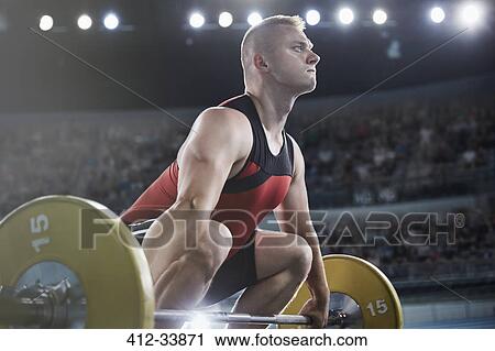 Stock Image - Focused male weightlifter lifting barbell. Fotosearch
