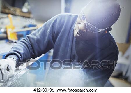 Stock Photography - Focused steel worker examining part in steel factory. Fotosearch