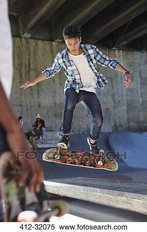 Focused teenage boy flipping skateboard at skate park View Large Photo Image Stock Photography - Focused teenage boy flipping skateboard at skate park. Fotosearch