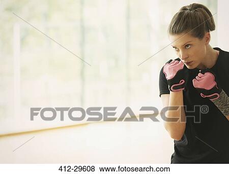 Stock Photo - Focused woman shadow boxing in gym studio. Fotosearch