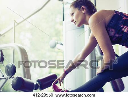 Stock Image - Focused woman stretching leg at gym. Fotosearch