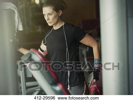 Stock Photograph - Focused woman stretching leg at gym. Fotosearch