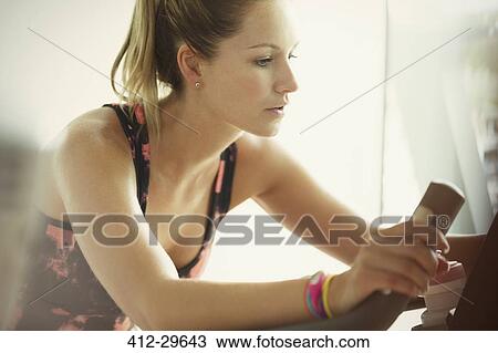 Focused woman using exercise bike at gym View Large Photo Image Stock Image - Focused woman using exercise bike at gym. Fotosearch
