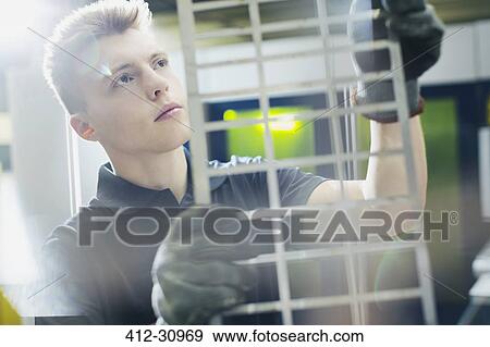 Stock Photo - Focused worker examining piece in steel factory. Fotosearch