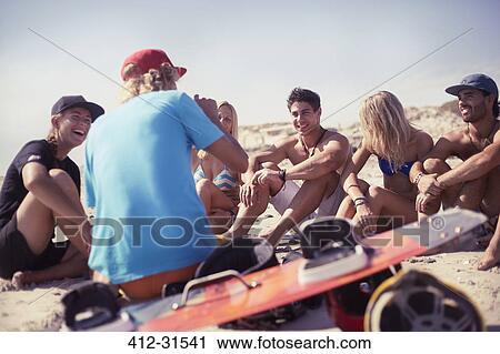 Stock Image - Friends learning kiteboarding on sunny beach. Fotosearch