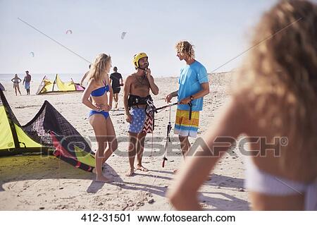 Stock Image - Friends learning to kiteboard on sunny beach. Fotosearch