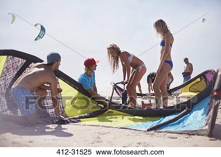 Stock Photography - Friends preparing kiteboarding kite on sunny beach. Fotosearch