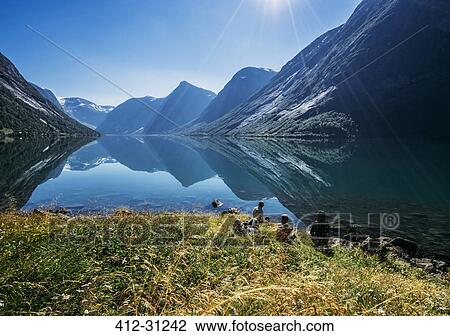 Stock Image - Friends relaxing at sunny tranquil mountain lakeside, Norway. Fotosearch