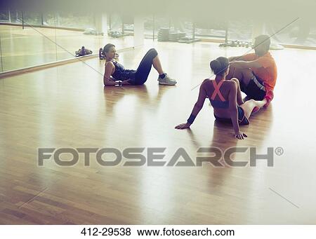 Friends resting and talking on gym studio floor View Large Photo Image Stock Photo - Friends resting and talking on gym studio floor. Fotosearch