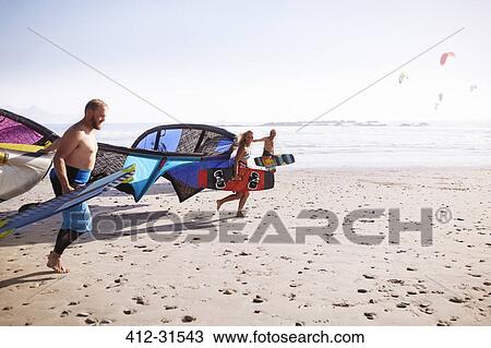 Friends running with kiteboarding kites on sunny beach View Large Photo Image Stock Image - Friends running with kiteboarding kites on sunny beach. Fotosearch