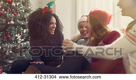 Friends talking and laughing near Christmas tree View Large Photo Image Picture - Friends talking and laughing near Christmas tree. Fotosearch