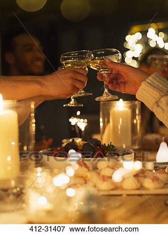 Friends toasting champagne glasses over table at candlelight Christmas dinner View Large Photo Image Stock Photo - Friends toasting champagne glasses over table at candlelight Christmas dinner. Fotosearch