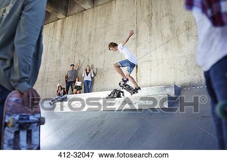 Friends watching and cheering teenage boy skateboarding at skate park View Large Photo Image Stock Photo - Friends watching and cheering teenage boy skateboarding at skate park. Fotosearch