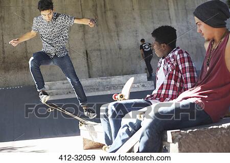 Friends watching teenage boy doing stunt at skate park View Large Photo Image Stock Photo - Friends watching teenage boy doing stunt at skate park. Fotosearch