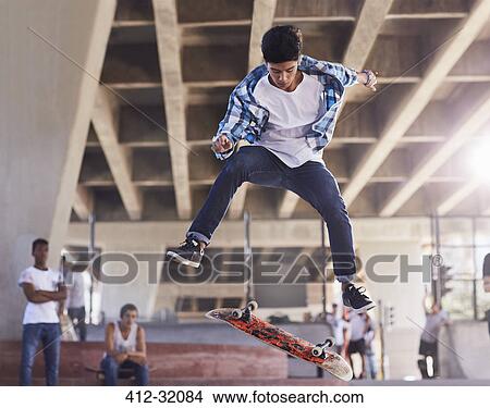 Friends watching teenage boy flipping skateboard at skate park View Large Photo Image Picture - Friends watching teenage boy flipping skateboard at skate park. Fotosearch
