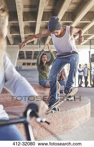 Friends watching teenage boy skateboarding at skate park View Large Photo Image Stock Image - Friends watching teenage boy skateboarding at skate park. Fotosearch