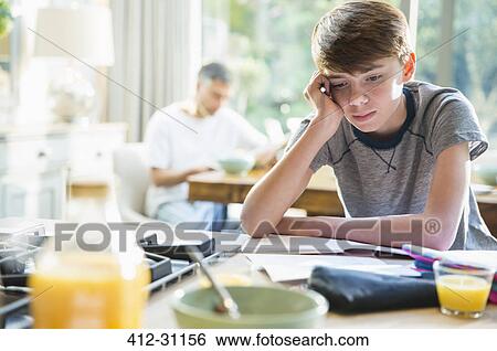 Stock Photograph - Frustrated boy doing homework at breakfast. Fotosearch