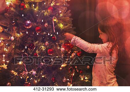 Girl decorating Christmas tree View Large Photo Image Stock Image - Girl decorating Christmas tree. Fotosearch