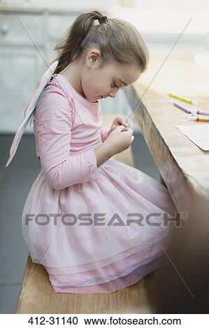 Girl in fairy wings coloring at dining table View Large Photo Image Stock Image - Girl in fairy wings coloring at dining table. Fotosearch