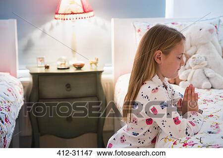 Girl in pajamas saying bedtime prayers at bed View Large Photo Image Stock Photo - Girl in pajamas saying bedtime prayers at bed. Fotosearch