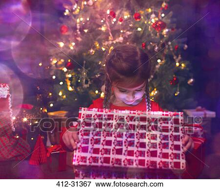 Stock Photo - Girl opening illuminated Christmas gift. Fotosearch