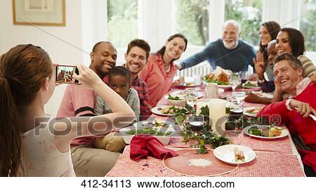 Girl with camera phone photographing multi-ethnic family at Christmas dinner table View Large Photo Image Stock Image - Girl with camera phone photographing multi-ethnic family at Christmas dinner table. Fotosearch
