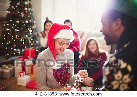 Girlfriend opening Christmas gift from boyfriend in living room View Large Photo Image Stock Image - Girlfriend opening Christmas gift from boyfriend in living room. Fotosearch