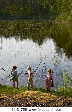 Stock Photograph - Girls fishing at sunny lakeside. Fotosearch