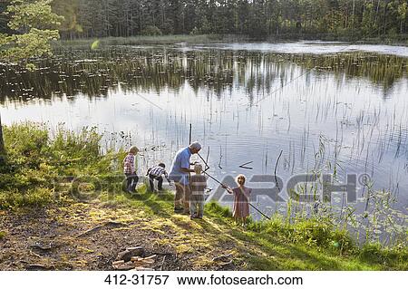 Stock Photo - Grandfather teaching grandchildren fishing at sunny lakeside. Fotosearch