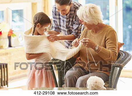 Grandmother knitting scarf around granddaughter View Large Photo Image Stock Photo - Grandmother knitting scarf around granddaughter. Fotosearch