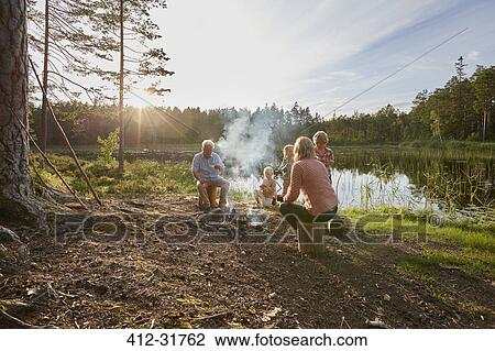Grandparents and grandchildren enjoying campfire at sunny lakeside in woods View Large Photo Image Stock Image - Grandparents and grandchildren enjoying campfire at sunny lakeside in woods. Fotosearch