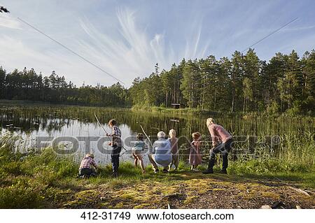 Stock Photo - Grandparents and grandchildren fishing at sunny lakeside in woods. Fotosearch