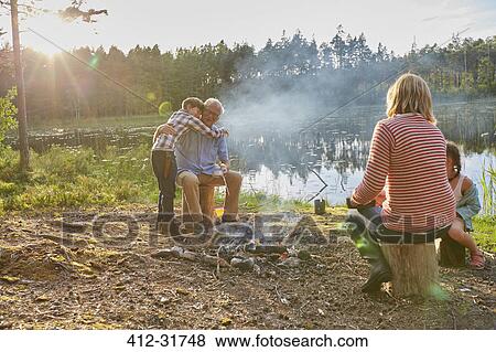 Grandparents and grandchildren hugging at campfire at sunny lakeside View Large Photo Image Stock Photo - Grandparents and grandchildren hugging at campfire at sunny lakeside. Fotosearch