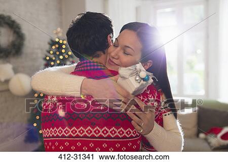 Grateful girlfriend with Christmas gift hugging boyfriend View Large Photo Image Stock Image - Grateful girlfriend with Christmas gift hugging boyfriend. Fotosearch