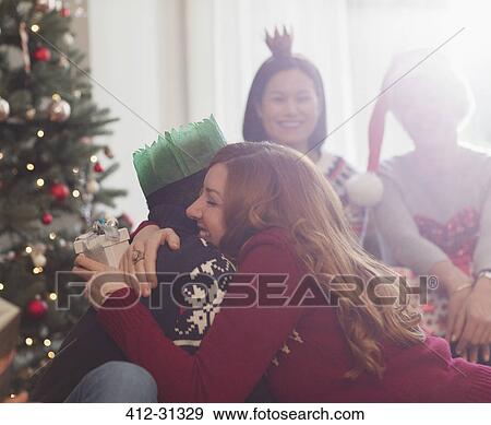 Stock Photo - Grateful girlfriend with Christmas gift hugging boyfriend. Fotosearch