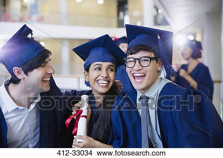 Picture - Happy college graduates in cap and gown celebrating with diploma. Fotosearch