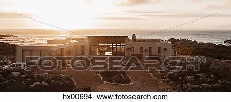 Picture - High angle view of luxury home overlooking ocean at sunset. Fotosearch