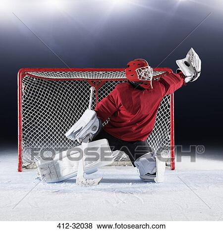 Hockey goalie in red uniform reaching for puck with glove at goal net View Large Photo Image Stock Photo - Hockey goalie in red uniform reaching for puck with glove at goal net. Fotosearch